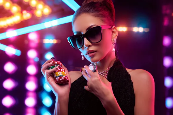 A young woman relaxing with her phone while dynamic casino elements float around her, illustrating the smooth mobile experience offered by the TKPKK app.