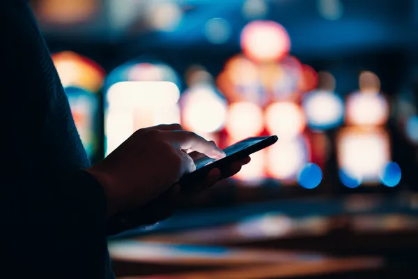 A stylish woman beside vibrant slot machines displaying glowing sevens, showcasing the variety of top slots at TKPKK.